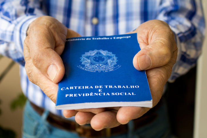 Elderly old male hands worker holding portfolio work permit of Ministry of Labor and Social Security of Brazil(Translation: "Work Permit, Ministry of Labor and Social Security of Brazil CTPS").